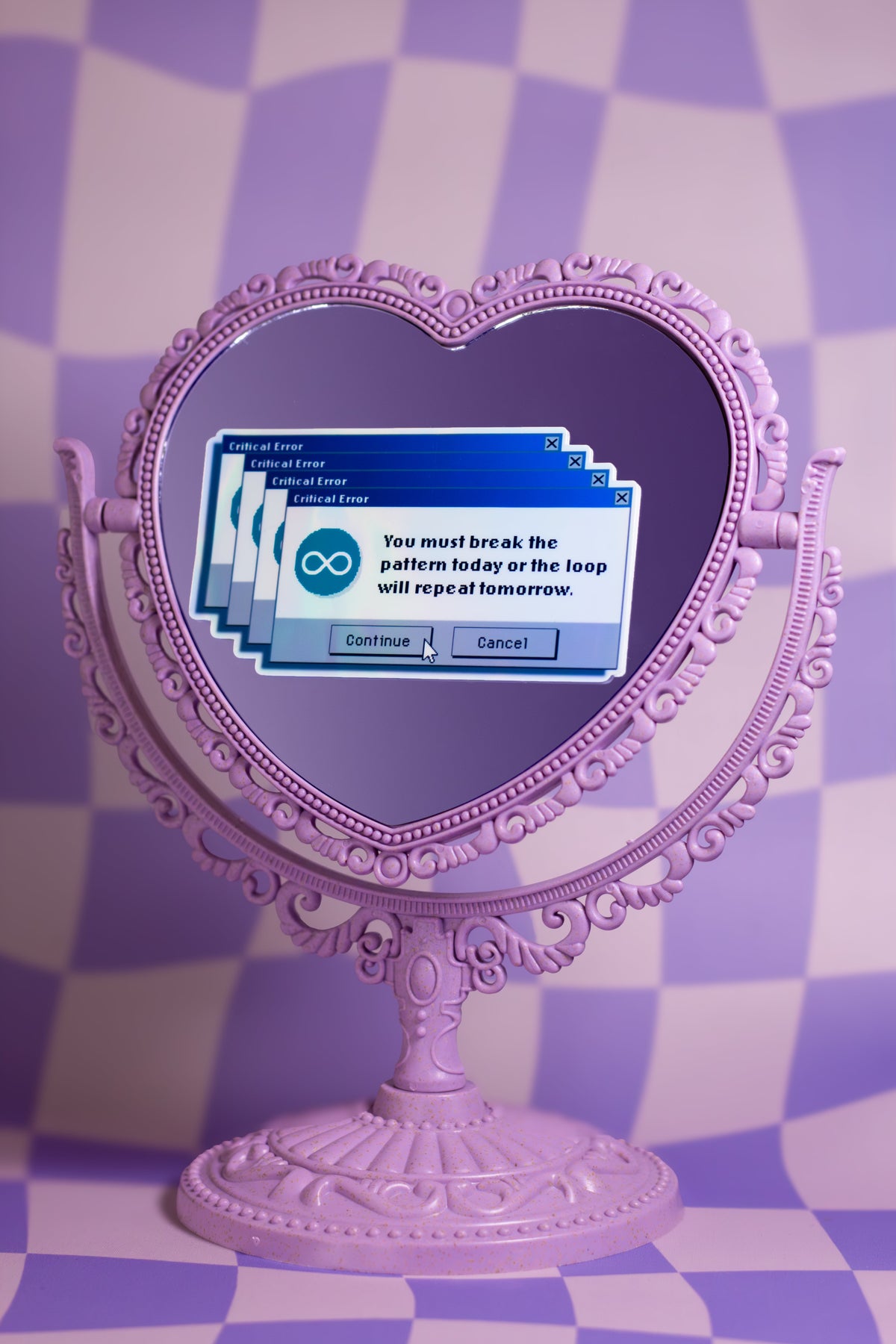 A decorative lavender heart-shaped mirror with an ornate stand, set against a purple and white checkered background. The mirror reflects a digital graphic of overlapping blue windows with a circular infinity symbol and the text 'You must break the pattern today or the loop will repeat tomorrow.