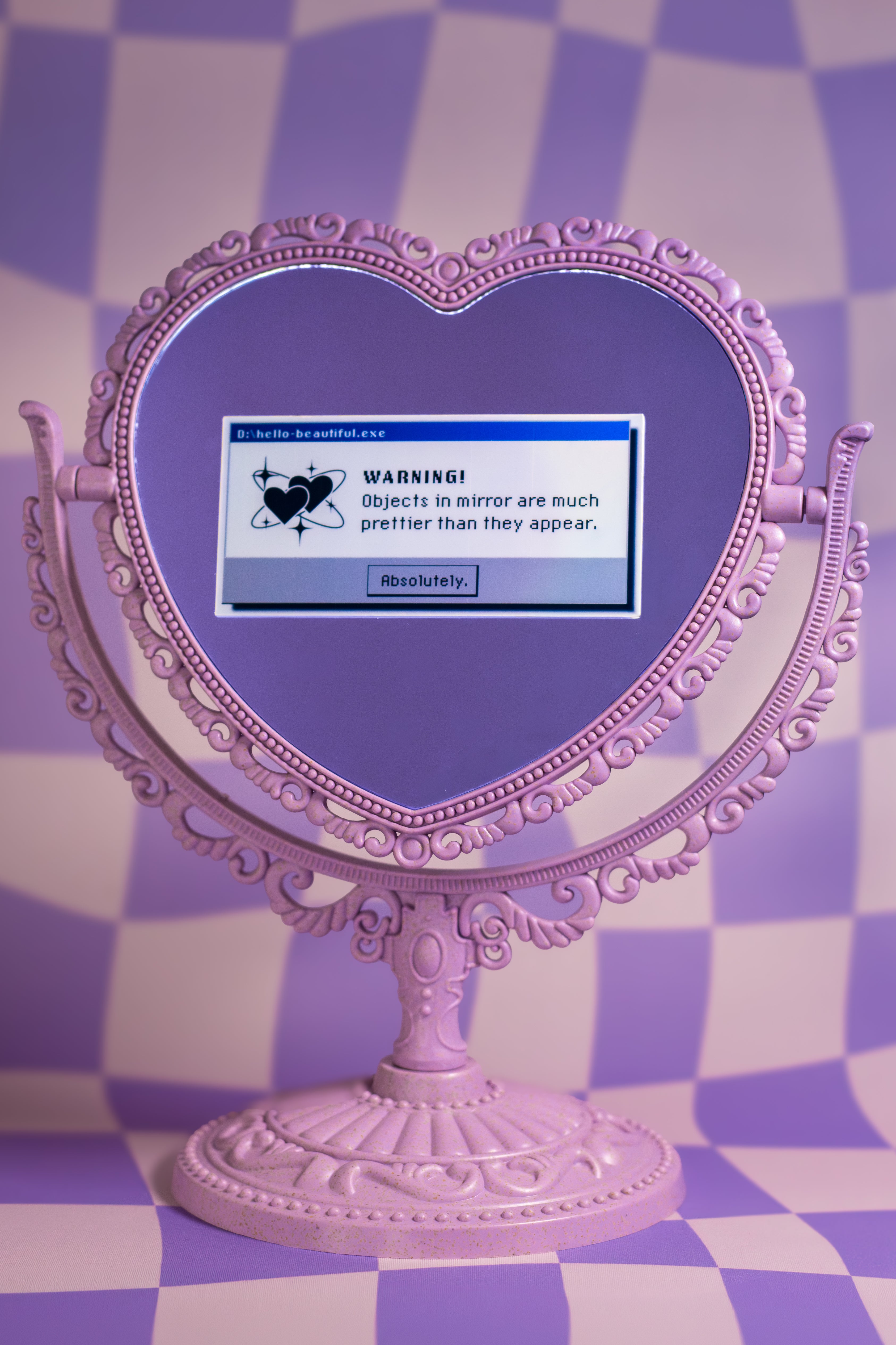 Pink heart-shaped mirror with a warning message on a checkered background